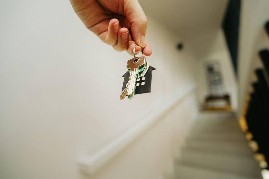 Une main tend un trousseau de clés dans le couloir d'une location saisonnière